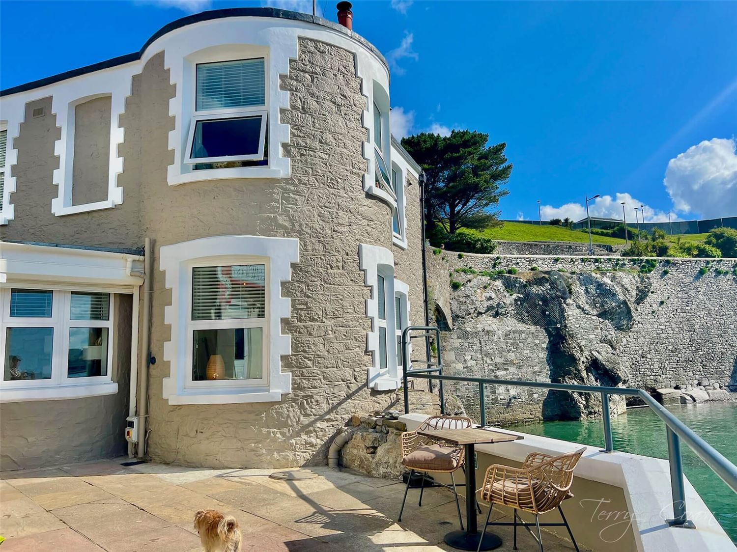The south facing view of the cottage exterior, the tide is in showing the close proximity to the waters edge abd beach steps
