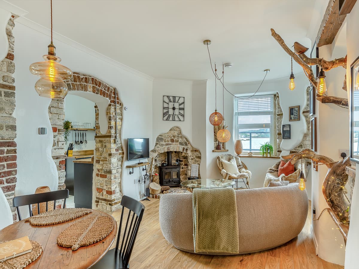 Open Plan lounge with curved sofa, log burner and sea views