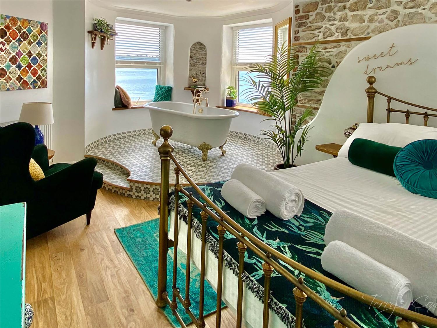 Rock Cottage bedroom shot towards the dual aspect windows over the roll top bath. Each window has a low sill for seating and taking in the view